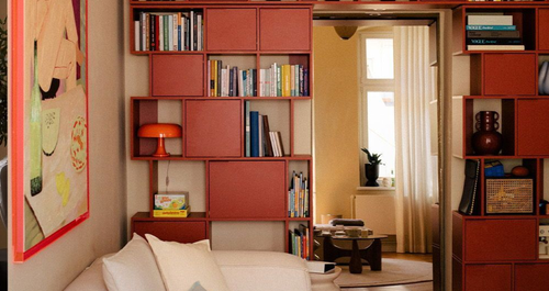 Μια κόκκινη βιβλιοθήκη σπάει την κυριαρχία του μπεζ σ’ αυτό το σαλόνι